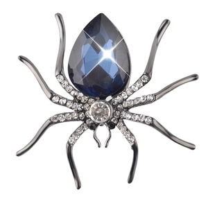 Detailed macro shot of a spider brooch featuring a large teardrop blue crystal and rhinestones