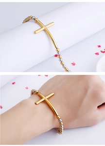 Detail of cross bead bracelet in gold and silver steel on model wrist and pedestal