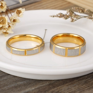 Two-tone brushed stainless steel couple rings with gold interior on decorative background