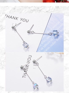 Detail of silver long drop earrings with iridescent cube crystal charms on marble