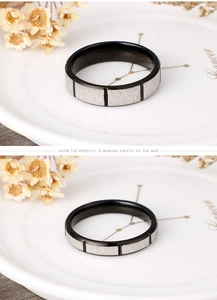 Detail view of black and silver brushed stainless steel couple rings on white ceramic