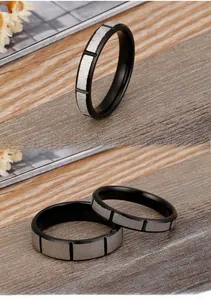 Detail of minimalist black stainless steel rings with brushed silver geometric inlay