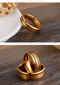 Detail of gold stainless steel couple rings with brushed finish and black enamel grooves