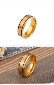 Macro detail of gold brushed stainless steel ring featuring dual black grooved stripes