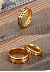Detail of brushed gold stainless steel rings featuring double black enamel parallel lines