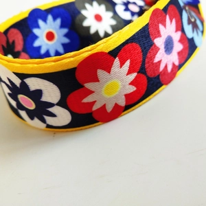 Detail of adjustable wide shoulder strap with floral daisy pattern and yellow piping