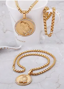 Détail du collier hip hop doré avec pendentif mains en prière orné de zircons