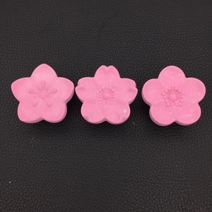 Detailed top view of three pink cherry blossom silicone molds on black leather background