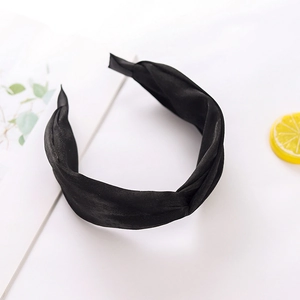 Detailed close-up of a black fabric knotted headband on a clean aesthetic background