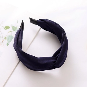 Detail of dark blue twisted fabric headband with velvet texture on a clean surface