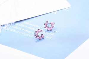 Macro shot of silver pinwheel stud earrings with pink rectangular zircon stones