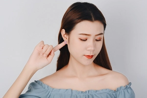 Close-up of a model wearing a minimalist pink zircon windmill stud earring in silver