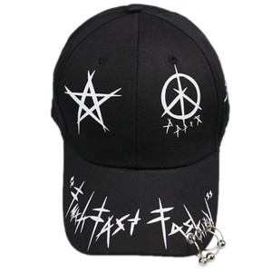 Détail d'une casquette punk noire avec anneaux métalliques et broderie Fast Fashion