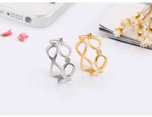 Detail of infinity symbol ring in gold and silver finish with zircon on desk background