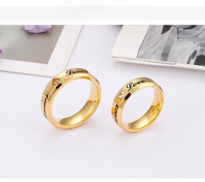 Detail of gold couple rings with Love Forever engraving and small round crystals