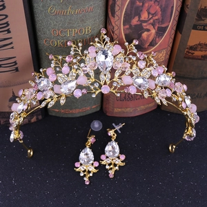 Detail of handmade gold bridal crown and earrings set with pink rhinestones on books