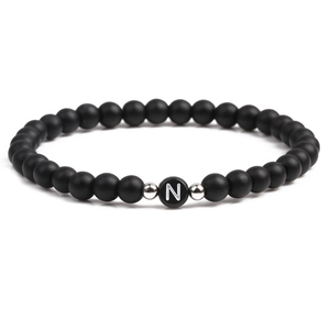 Detail shot of black matte beaded bracelet featuring a white letter N on a central bead