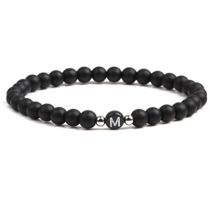 Macro detail of 6mm black matte bead bracelet with silver spacers and letter M charm