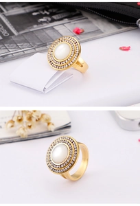 Detail of gold titanium ring featuring white cat eye stone and double rhinestone halo