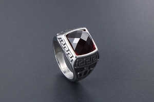 Detailed side view of men's steel ring with dark red gemstone and Greek key patterns