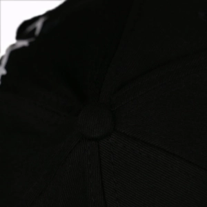 Detailed close-up of the black baseball cap crown showing stitching and top fabric button