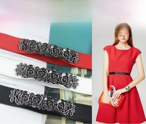 Detail of elastic waist belts in red, white and black with embossed metal rose buckles