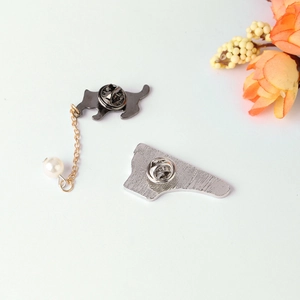 Detail of cartoon cat brooch back with metal butterfly clasp and chain pearl pendant