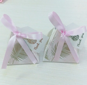 Detail of pink palm leaf wedding favor box with thank you tag and satin ribbon