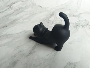 Macro view of a matte black resin cat phone stand showing the ergonomic support curve