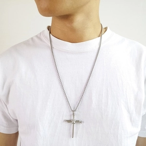 Macro shot of silver stainless steel cross pendant made of tied nails on a thin chain