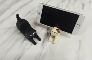 Detail of cute resin cat phone holder in black and calico cat stretching poses