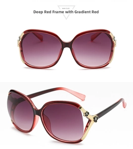 Detail view of dark red gradient sunglasses with gold camellia flower hinge decoration