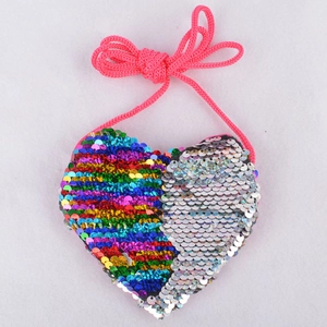 Macro shot of heart-shaped mini sequin bag with rainbow and silver details on white background