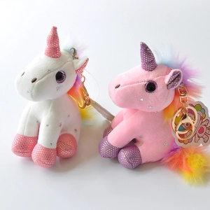 Detailed macro view of plush unicorn keychains with gold metal rings in white and pink