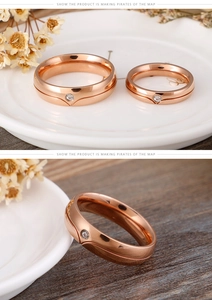Close-up of rose gold couple rings featuring a single sparkling crystal on a white plate