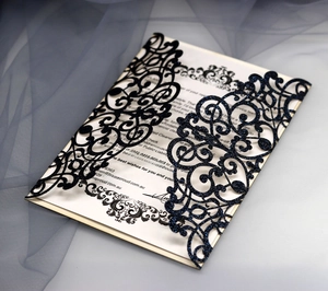 Detail of laser-cut navy glitter invitation with elegant vintage vine patterns