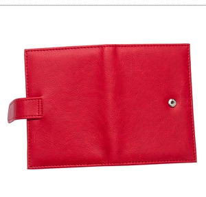 Detail of red PU leather passport holder featuring fine stitching and secure buckle strap