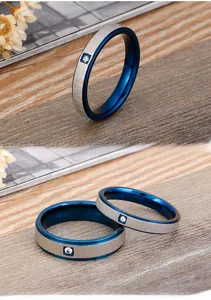 Detail of couple rings with silver brushed finish and blue inner band set with a single stone