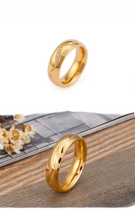 Détail d'une bague en acier doré avec texture ondulée et trois pierres de zircone