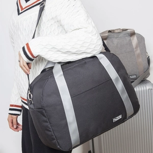 Große schwarze Reisetasche mit grauen Gurten und Logo, präsentiert mit einem Koffer