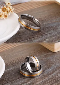 Detail of brushed titanium steel rings with gold inlay and zircon stones for couples