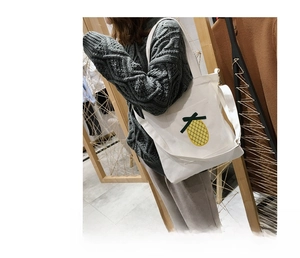 Detail of white canvas tote bag featuring a cute yellow pineapple embroidery patch