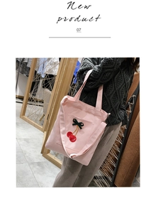Pink canvas tote bag featuring 3D embroidered cherries shown on a shoulder strap