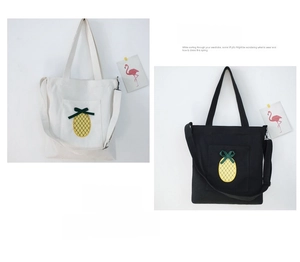 Detail of canvas tote bags featuring cute pineapple embroidery and functional front pocket
