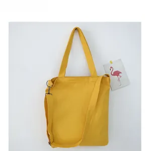 Detail view of bright yellow canvas tote bag with adjustable shoulder strap and dual handles
