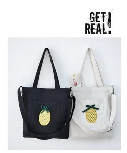 Detail of canvas tote bags with pineapple embroidery and ribbon bows in black and white