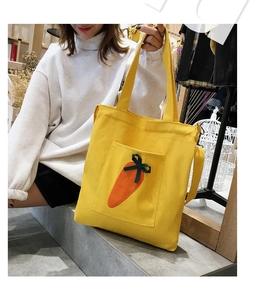 Detail view of yellow canvas tote bag featuring a cute carrot patch and exterior pocket