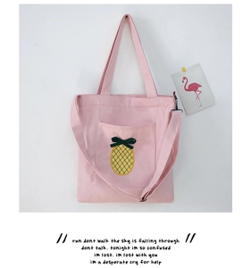 Detailed view of pink canvas tote bag featuring pineapple pattern and dark green bow