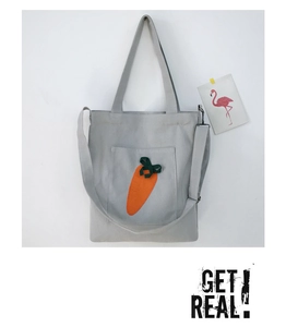 Detail of grey canvas tote bag featuring an orange carrot embroidery and shoulder strap