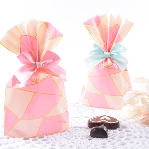 Pink plaid gift bags with ribbons and gold geometric patterns on lace placemat